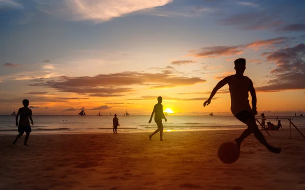 Закат силуэты, играть в пляжный футбол Стоковое Изображение