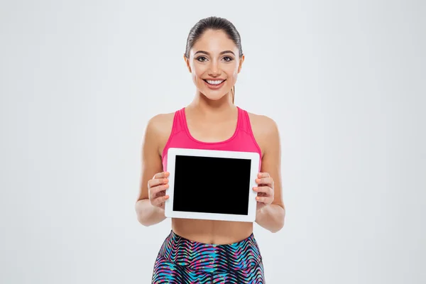 Улыбается женщина спорта, показывая пустой планшетный компьютер экран Стоковое Изображение