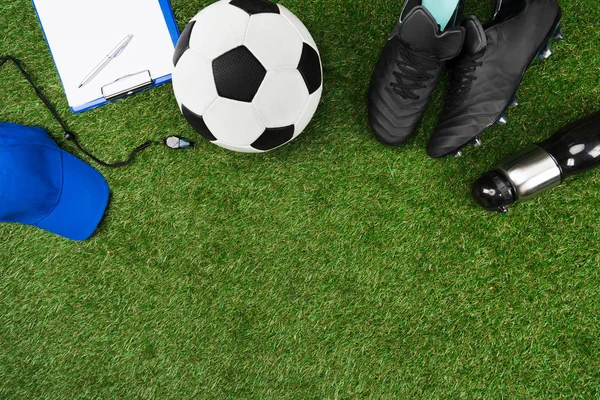 Буфер обмена с футбольный мяч и сапоги на траве Стоковая Картинка