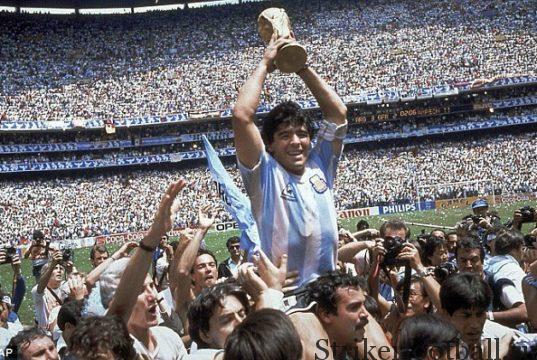 Безоговорочно лучший футболист мира Диего Марадона держит над головой Кубок Жюля Римэ на восхищенном стадионе «Ацтека* в Мехико.
