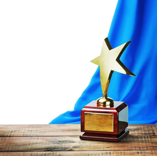 Звезда премии деревянный стол и на фоне голубой занавес Стоковое Фото