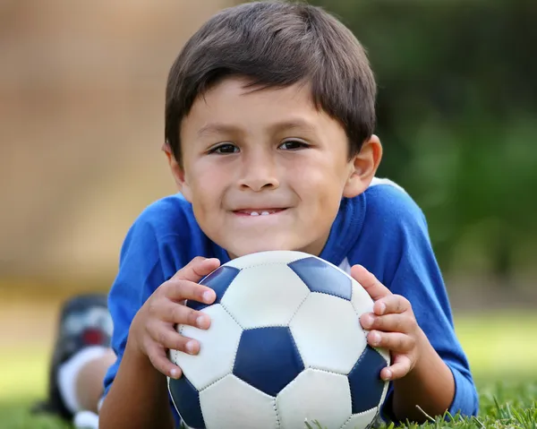 Испаноязычное мальчик лежа с футбольным мячом Лицензионные Стоковые Изображения