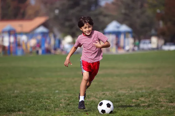 Мальчик играет в футбол в парке Лицензионные Стоковые Изображения