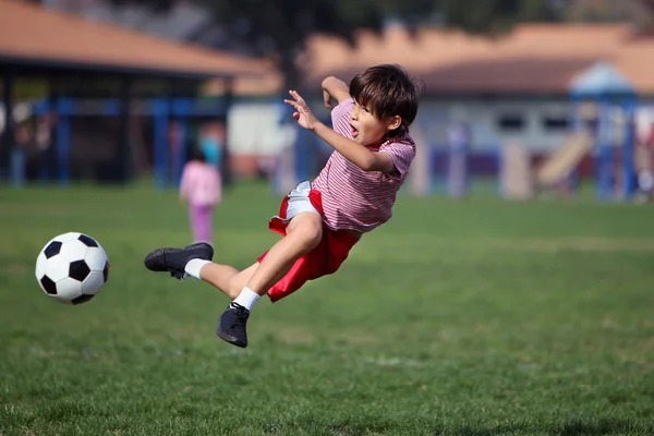 Мальчик играет в футбол в парке Лицензионные Стоковые Фото
