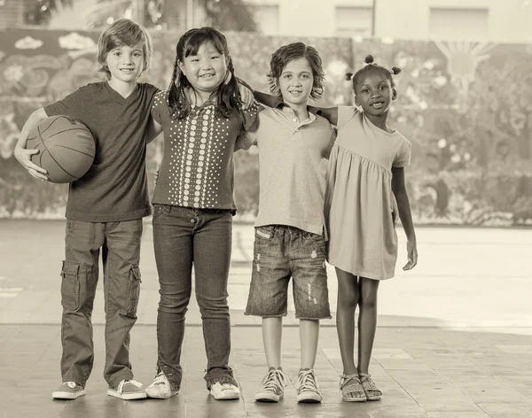 Начальная школа дети, играя баскетбол в спортзале Стоковое Фото