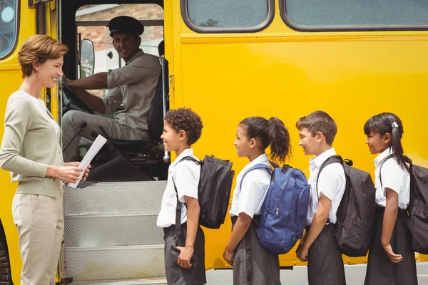 Симпатичные школьников, ожидая получить на школьный автобус Стоковое Изображение