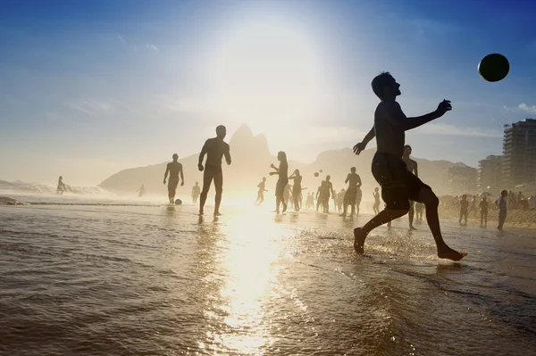 Силуэты бразильцев, играя Altinho пляжный футбол Рио Лицензионные Стоковые Изображения