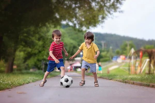Две Симпатичные маленькие дети, вместе играть в футбол, летнее время Лицензионные Стоковые Фото