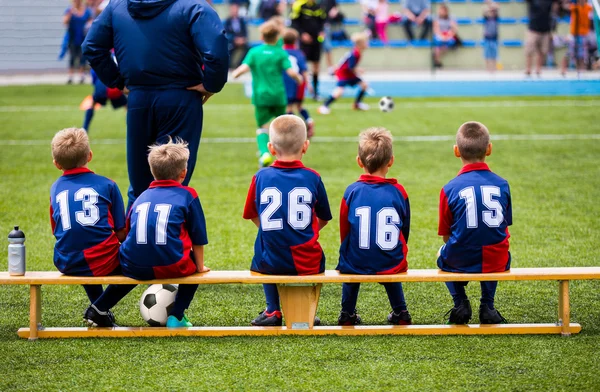 Футбольный футбольный матч для детей. дети, смотрящие игру с тренером тренера и ждущие на скамье Стоковое Фото
