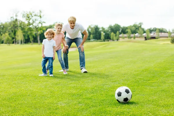 Отец с детьми, играть в футбол в парке Лицензионные Стоковые Изображения