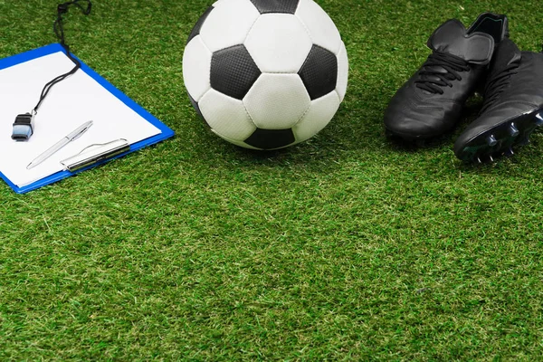 Буфер обмена с футбольный мяч и сапоги на траве Стоковое Фото