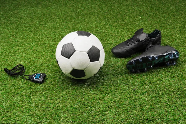 Секундомер с футбольный мяч и сапоги на траве Стоковое Изображение