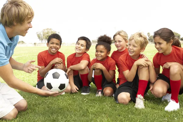 Маленькие мальчики и девочки в футболе подходят к тренеру Лицензионные Стоковые Изображения