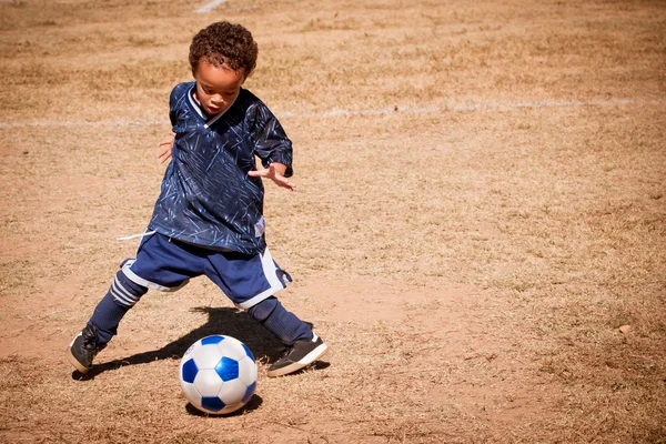 Молодые афро-американский мальчик играет в футбол Стоковое Фото